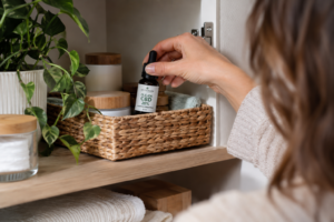 Olejek CBD przechowywany w domowej szafce obok kosmetyków, w tym kremu CBD